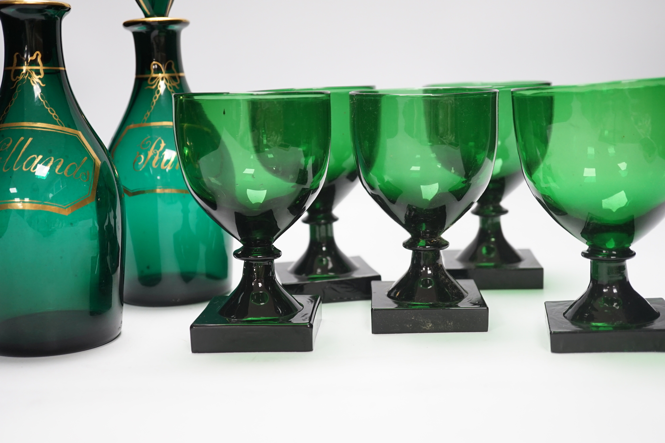 A pair of small Bristol green decanters, Rum and Hollands, c.1800 and five 19th century green glass rummers, with lemon squeezer bases, decanters 22cm high